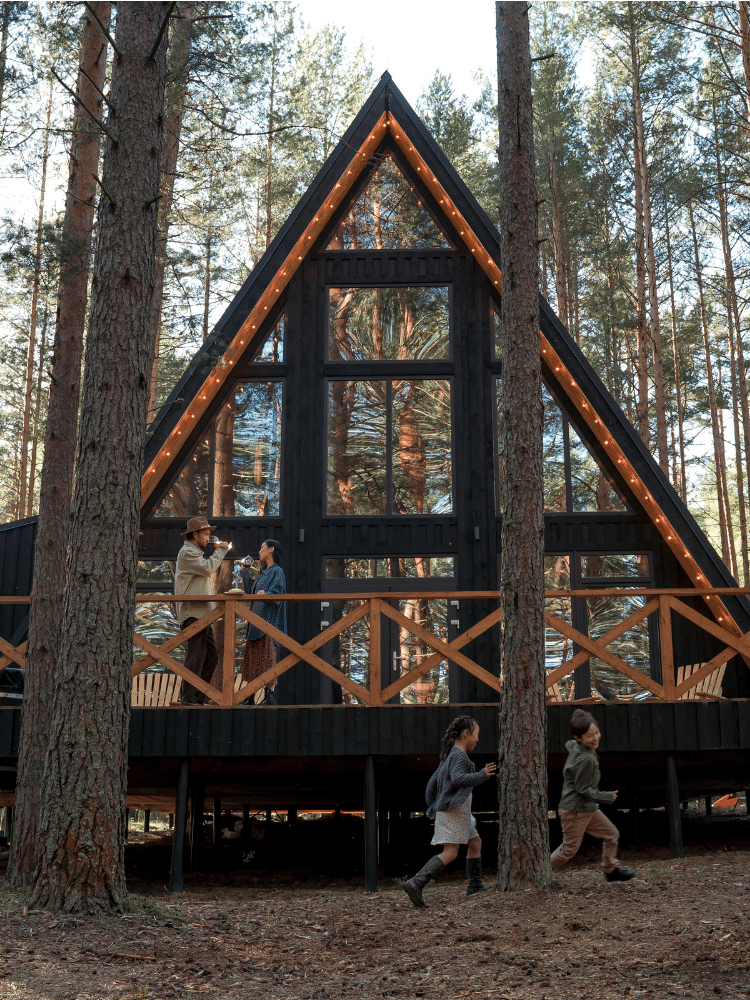 House in the woods with family playing outside.
